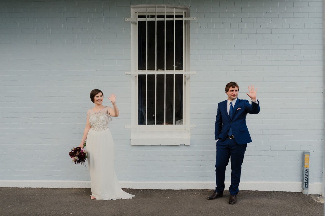 Wedding couple waves at passerby
